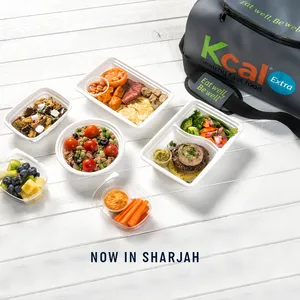حقيبة خطط وجبات كي كال على الطاولة مع مجموعة مختارة من الوجبات الصحية مع نص يوضح الآن في الشارقة
