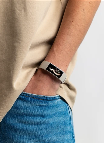 A person wearing a smartwatch displays the time and steps on the screen, with one hand in their jeans pocket, against a plain white background.