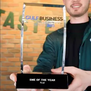 Man in a green Kcal jacket holding Kcal's SME of the Year Award from 2015