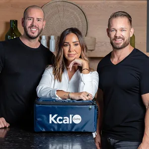 Mark Carroll, Chef Hala and Andreas L Borgmann standing in a kitchen behind a Kcal Meal Plans bag.