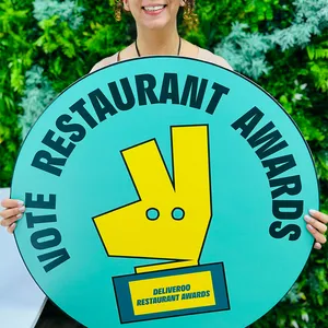 Woman holding a sign saying vote restaurants awards for Best Healthy Restaurant.