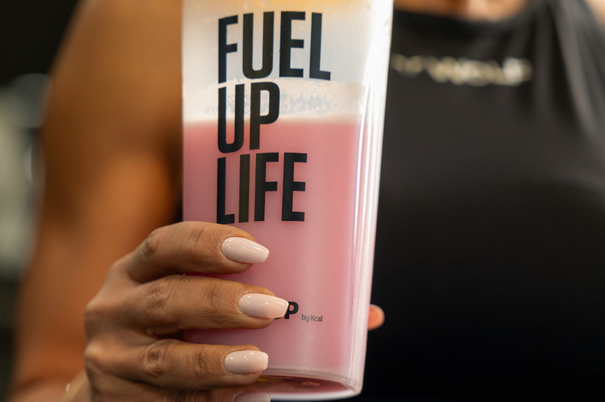 Woman in the gym holding a strawberry protein shake