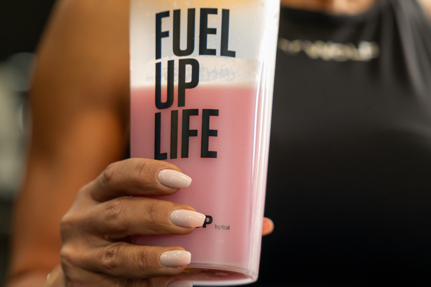 woman in the gym holding a strawberry protein shake