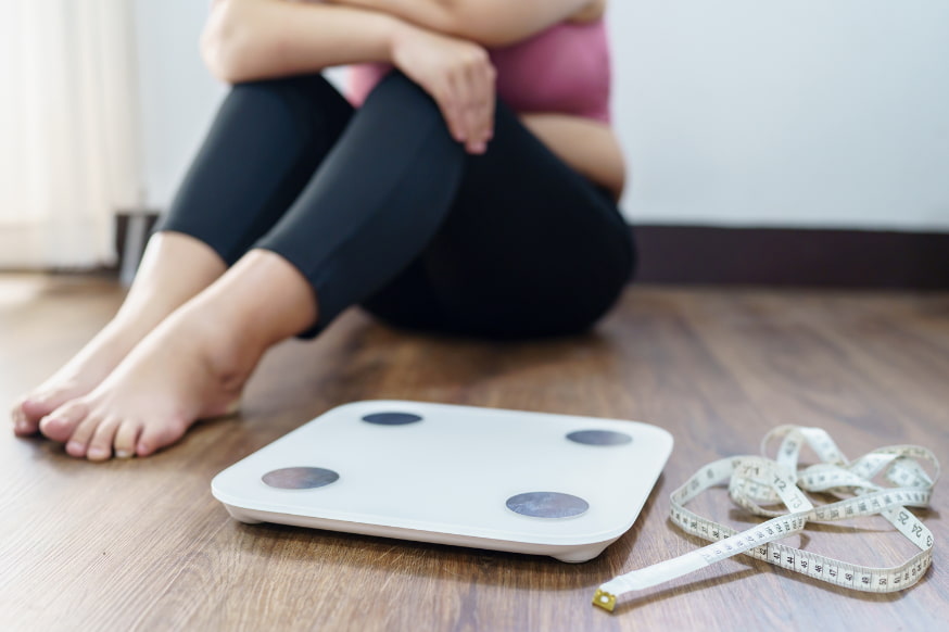 Woman sitting on the floor next to scales