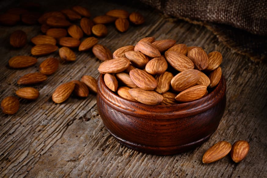 Bowl of almonds on a wooden benchtop