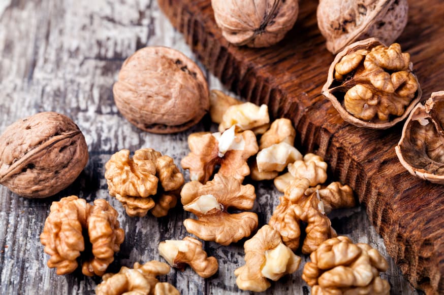 Raw walnuts, both shelled and de-shelled placed on a wooden cutting board