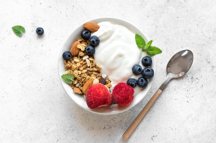 Fresh yoghurt in a white bowl served with oats, nuts and fresh berries