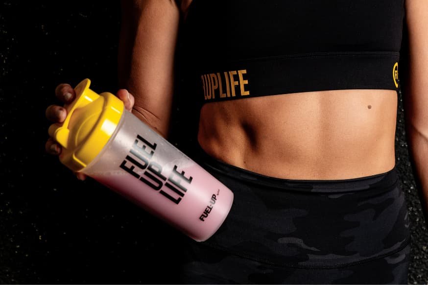 Woman holding a fuel-up protein shake by her side for a healthy snack