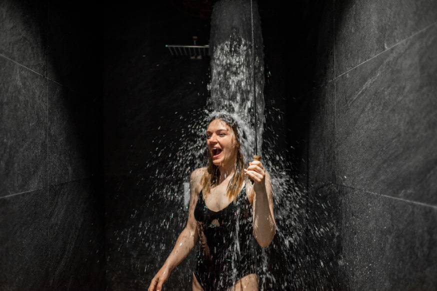 Woman in a swimming costume taking a refreshing cold shower.