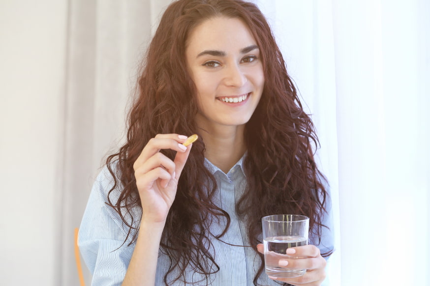 Woman holding a multivitamin and a glass of water. 