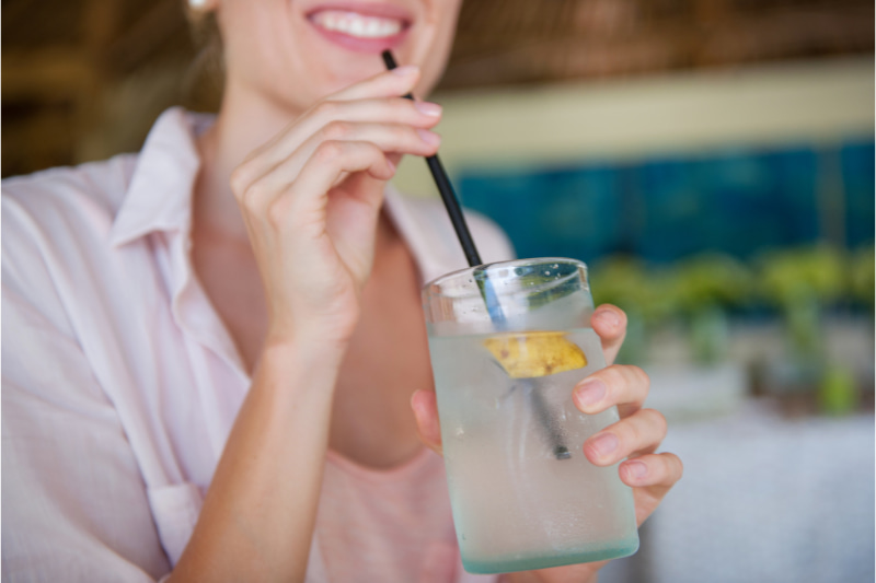 Woman drinking coconut water to rehydrate after night of consuming alcohol